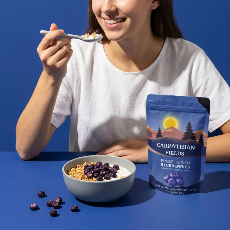 Smiling woman eating granola with freeze-dried blueberries next to pouch
