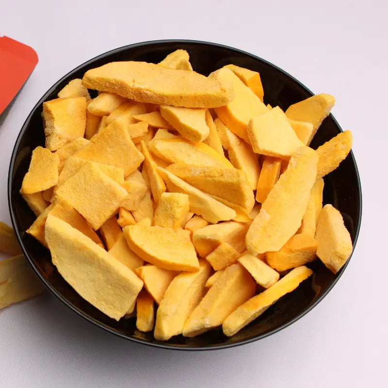 Freeze-dried mango slices served in a black ceramic bowl