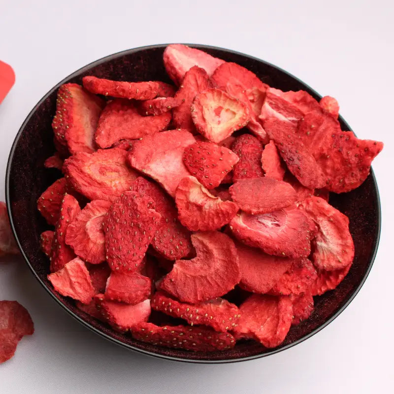 Crisp freeze-dried strawberry slices served in a black bowl