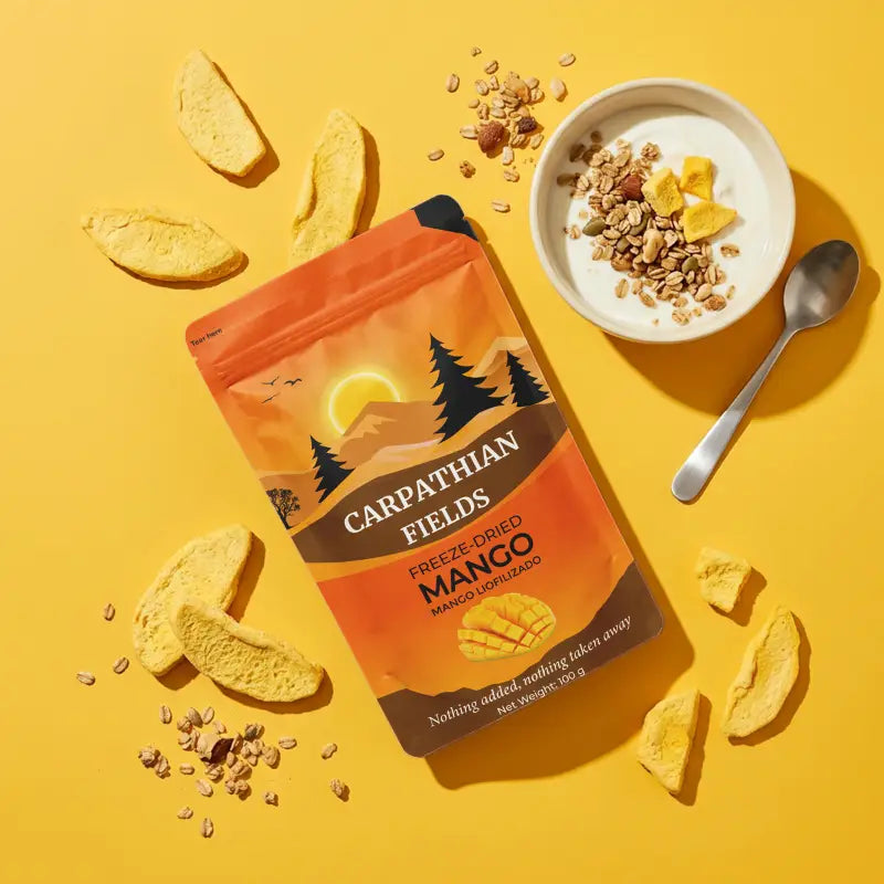 Overhead flatlay of freeze-dried mango pouch, yogurt bowl, and scattered slices