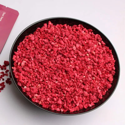 Freeze-dried raspberry crumbs served in a black ceramic bowl